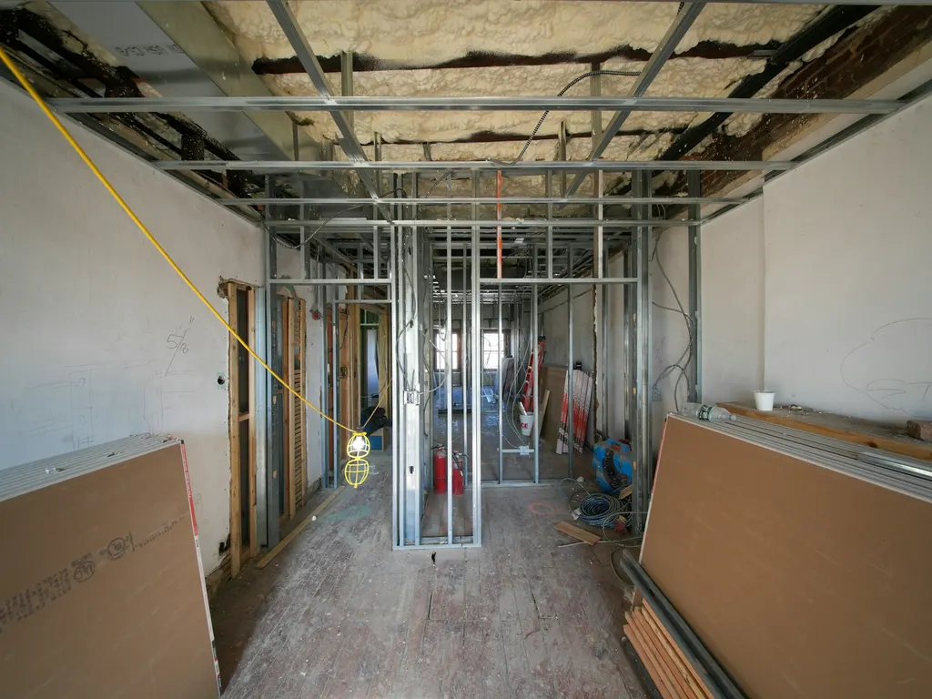 Interior under construction with metal framing and drywall sheets during wall installation
