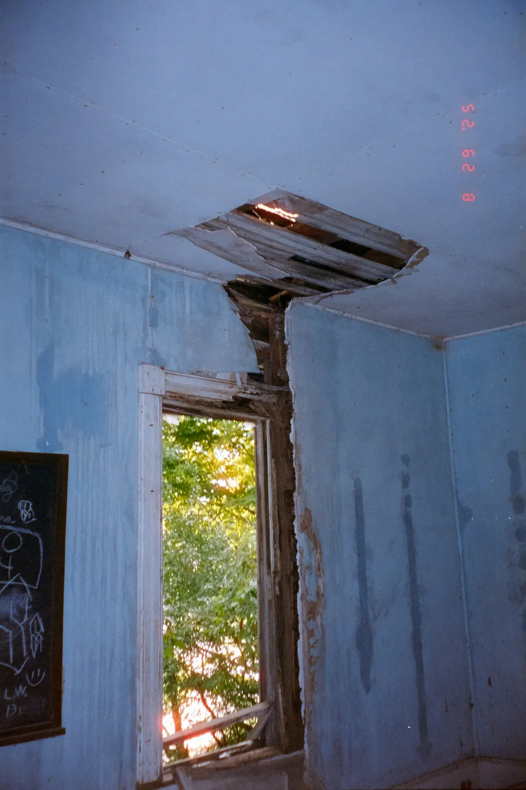 Water-damaged room with a large ceiling opening and exposed roof structure